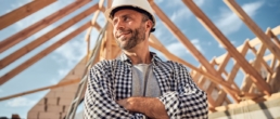 Contented young architect standing cross-armed in the middle of a wooden construction